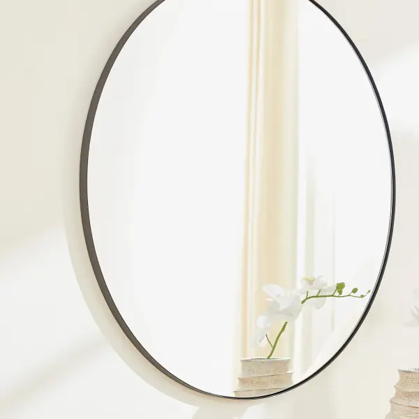 This 36-inch round mirror combines minimalist design with versatile styling. The matte black finish adds contemporary sophistication while remaining neutral enough to complement any décor scheme. - alternate view