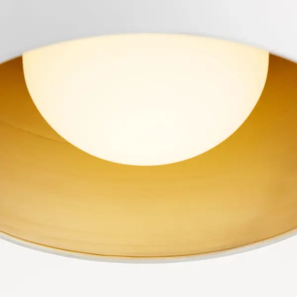 This 11-inch flush mount combines a clean white glass exterior with an unexpected aged brass interior, creating visual interest while maintaining versatility. The compact profile works beautifully in hallways, entryways, and patios. - alternate view