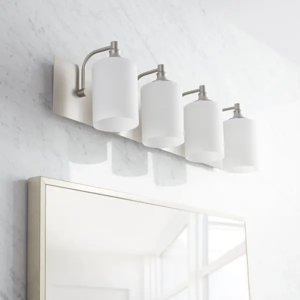 The Celeste 4-light vanity combines sleek satin nickel with soft opal glass for a sophisticated, versatile look. Its minimalist design adds contemporary elegance while maintaining transitional flexibility for various bathroom styles. - alternate view