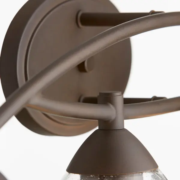 The Barkley 4-Light Vanity combines sinuous tube frames with clear seeded glass shades, creating a fixture that bridges traditional and contemporary design. Its oiled bronze finish and symmetrical profile work seamlessly across multiple interior styles. - alternate view