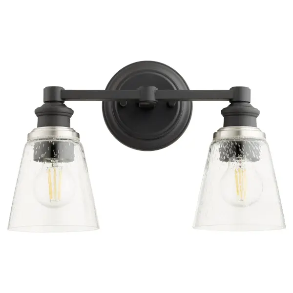 The Dunbar 2-Light Vanity blends nostalgic refinement with contemporary design through clear seeded glass shades and sharp angles. Features interchangeable socket cup decos in noir, satin nickel, and aged brass for personalization. - alternate view