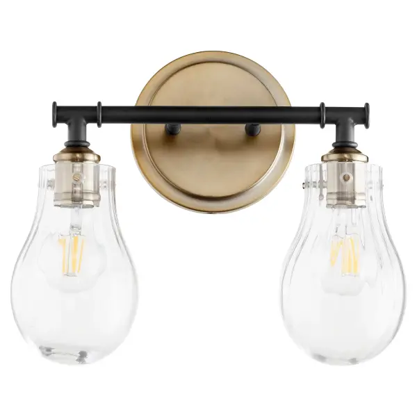 This two-light vanity fixture brings nostalgic 50's charm with contemporary flair. The striking black and aged brass finish combination paired with clear fluted glass shades creates an eclectic, sophisticated look perfect for modern bathrooms.