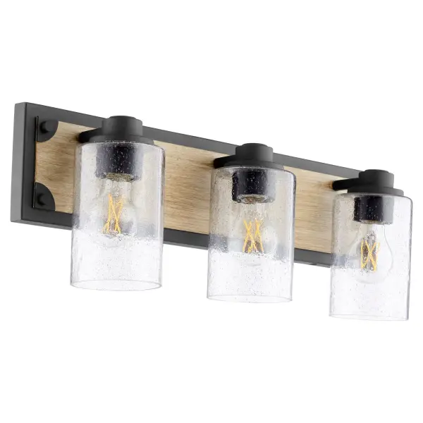 This 3-light vanity fixture combines rustic farmhouse aesthetics with industrial design elements. The two-toned driftwood and noir finish paired with clear seeded glass creates authentic character perfect for modern farmhouse bathrooms.