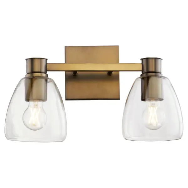 The Relo 2-Light Vanity combines traditional bell-shaped clear glass shades with a sophisticated dark brass frame, creating a transitional aesthetic that works in both classic and contemporary bathrooms. - alternate view