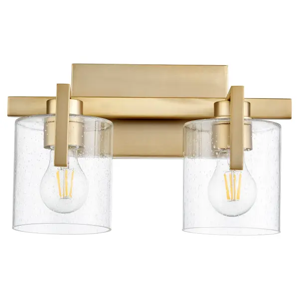 This two-light vanity fixture combines classic seeded glass shades with warm aged brass finish for versatile bathroom lighting. The rectangular backplate and round shades create visual interest while providing ample illumination.