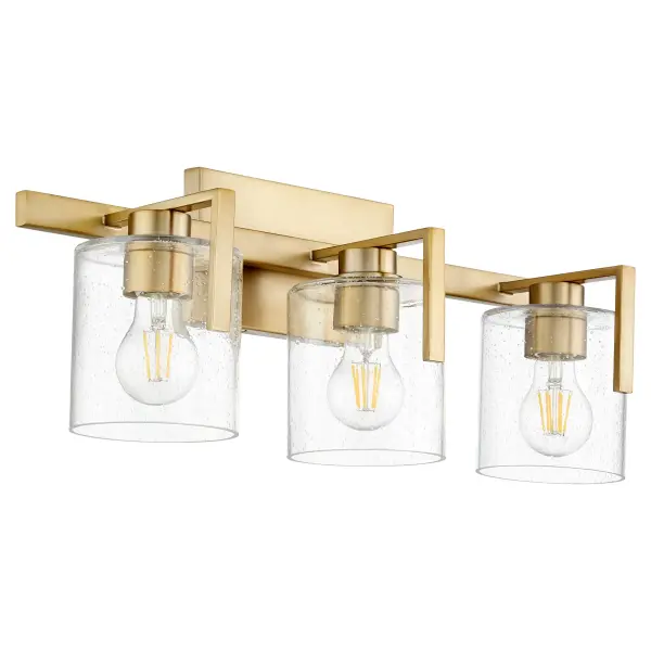 This three-light vanity fixture combines classic seeded glass shades with an aged brass finish for sophisticated bathroom lighting. The rectangular backplate and round shades create visual interest while providing ample illumination.