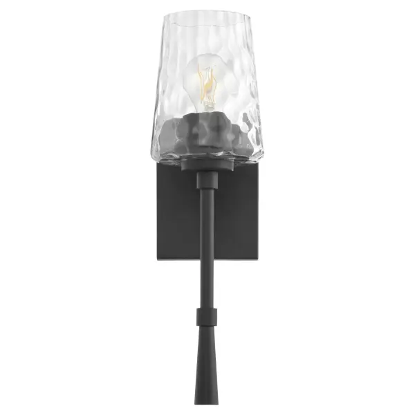The Goodwin wall sconce combines sleek matte black framing with textured hammered glass for a sophisticated look. Its single-light design provides focused illumination perfect for hallways, bathrooms, and accent lighting.