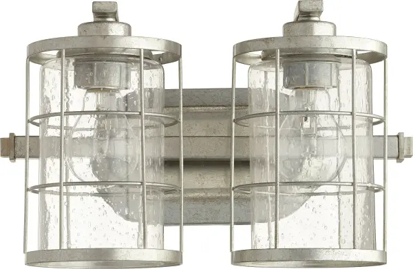 The Ellis 2-Light Vanity combines industrial charm with farmhouse warmth through its distinctive caged exterior and clear seeded glass shades. Compact yet characterful, this fixture delivers modern minimalism with rustic appeal.