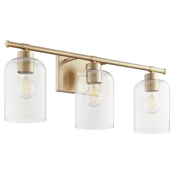 The Tribute 3-Light Vanity combines classic comfort with contemporary clean lines. Clear glass shades and aged brass finish create an effortless design suitable for both indoor bathrooms and covered outdoor spaces.