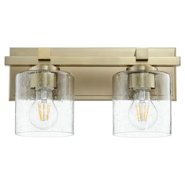 This two-light vanity fixture blends traditional brass elegance with contemporary seeded glass for a sophisticated bathroom upgrade. The aged brass finish adds warmth while clear seeded glass shades provide ambient illumination.