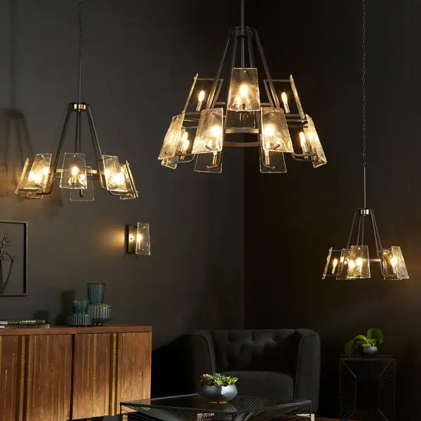 The Tioga chandelier masterfully blends Mid-Century Modern design with transitional appeal through its conical shape, linear framing, and frosted glass trapezoid shades. The Aged Brass-Noir finish combination creates nostalgic charm while maintaining contemporary minimalism. - alternate view
