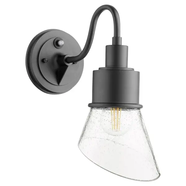 The Torrey wall light combines industrial and rustic elements with a softly curved arm and hood shade. Its Wet rating makes it perfect for outdoor use, while the clear seeded glass and noir finish create a versatile look suitable for various settings.