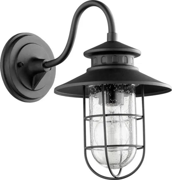 The Moriarty wall light combines coastal charm with rustic durability. Its caged clear glass design and black finish create welcoming illumination for entryways, porches, and outdoor living spaces.