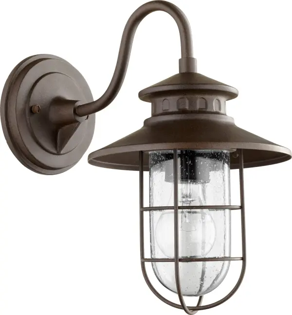 The Moriarty wall light combines rustic warmth with coastal durability in a compact 13" fixture. Its caged clear glass design and oiled bronze finish deliver character and welcoming illumination for outdoor entryways and accent areas.