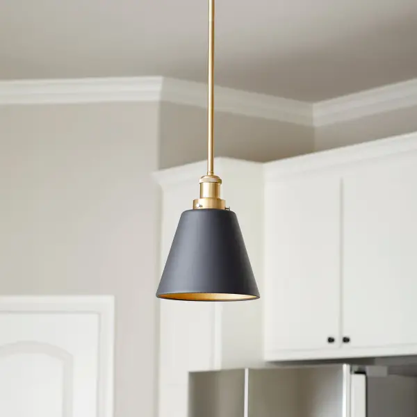 This eclectic one-light pendant blends modern industrial aesthetics with transitional warmth through its distinctive two-tone finish. The cone shade features opaque black exterior with aged brass interior, creating ambient glow while adding visual interest. - alternate view