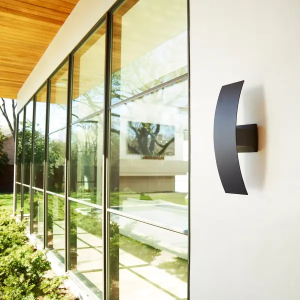 The Curvo brings futuristic style to outdoor spaces with its curved silhouette and efficient dimmable LED technology. The noir black finish and frosted acrylic shade create ambient lighting perfect for covered patios and entryways. - alternate view