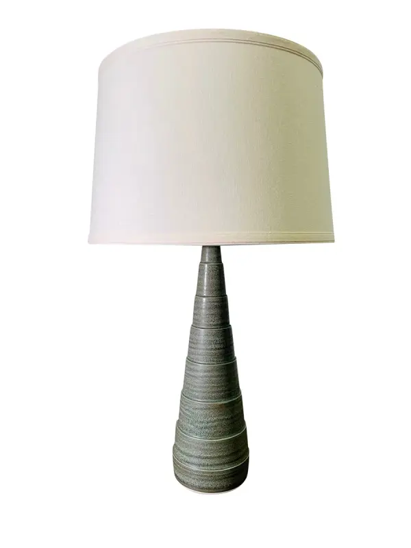 The Scatchard table lamp combines timeless ceramic craftsmanship with a contemporary green matte finish. At 26.5" tall, it provides substantial presence while the neutral off-white shade ensures versatile styling across traditional and modern interiors.