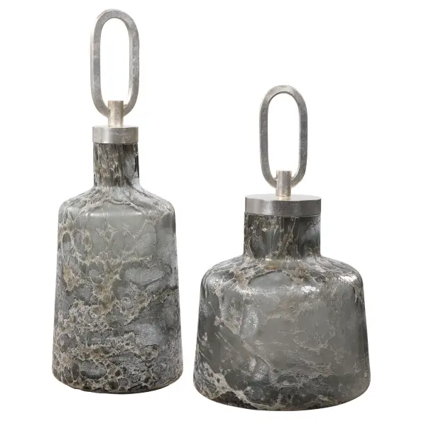 This set of two art glass bottles brings heavy texture and soft neutral color to shelves or tabletops, finished with a silver leaf iron top accent.