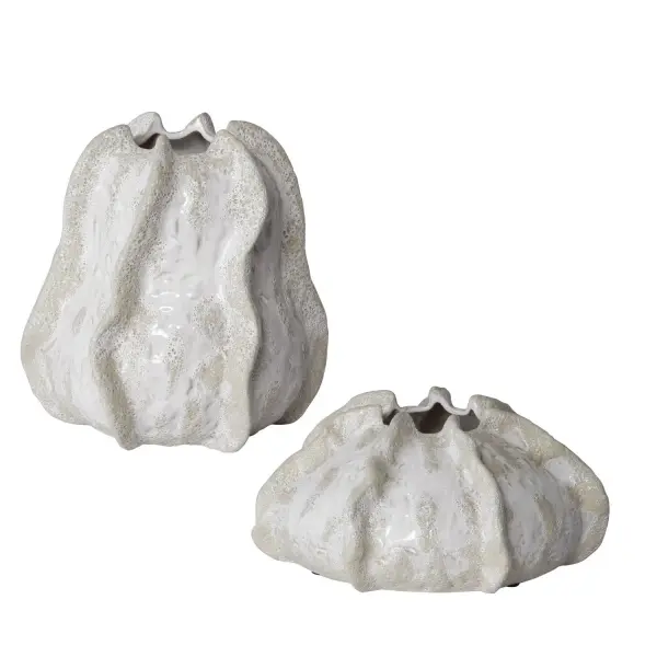 A set of two ceramic vases in an ivory and beige glaze with sandy texture and organic curves, evoking relaxed coastal style for shelves, tables, or mantels.