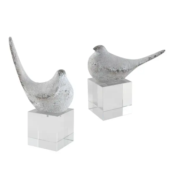 A decorative set of two bird figurines in a distressed textured silver finish atop chunky crystal blocks—a tactile, artisanal accent for shelves or tabletops.