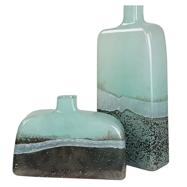 This set of two uniquely shaped glass vases blends aqua and bronze tones with an opalescent border, offering an artisanal accent for shelves, consoles, or tables.