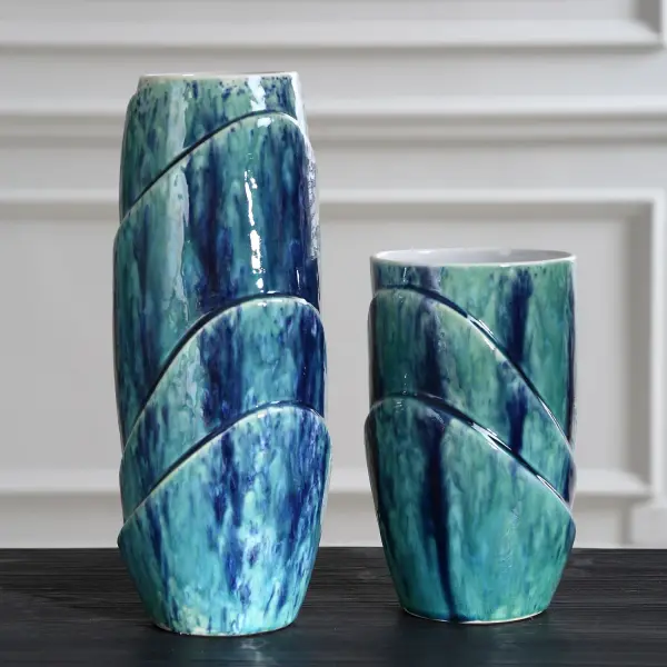 A set of two ceramic vases in a blue and green reactive glaze with contrasting white interiors, each with a unique organic pattern. Best for indoor decorative display.