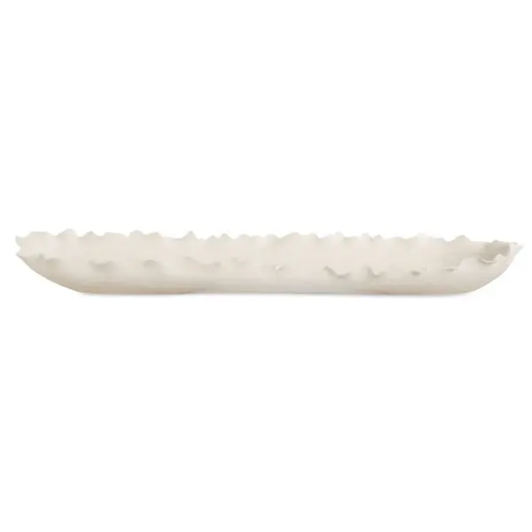 An elongated matte white ceramic bowl with delicately ruffled edges, blending organic coastal form with modern minimalist styling for tabletop display.