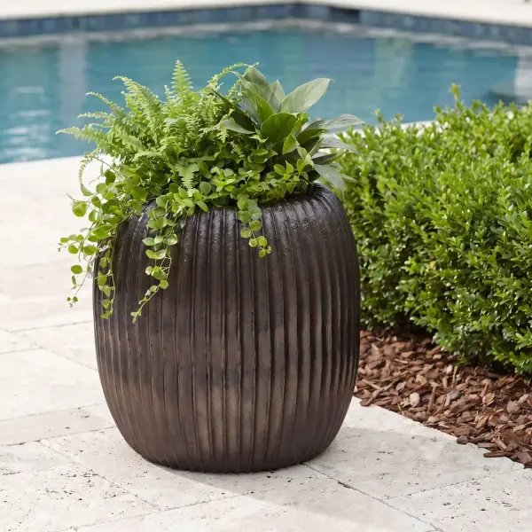 A cast aluminum planter with deep vertical ribbing and a dark, weathered finish, suited to modern and industrial spaces indoors or out.