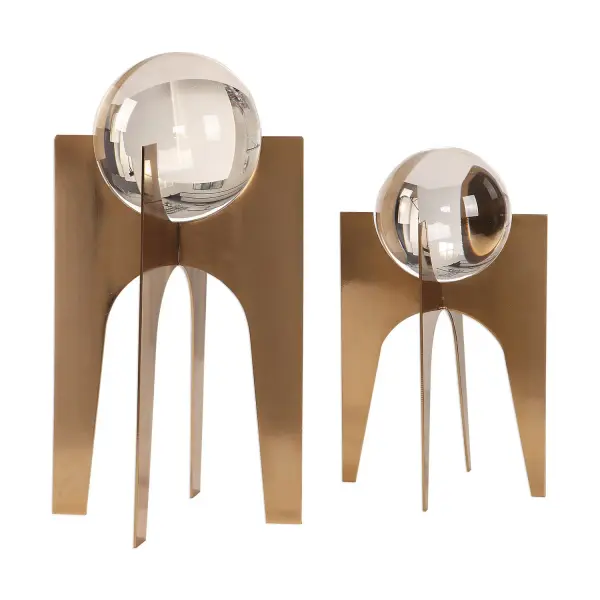 A set of two faceted crystal spheres on brushed copper bronze stainless steel bases, offering understated glamour for tabletops, shelves, and consoles.
