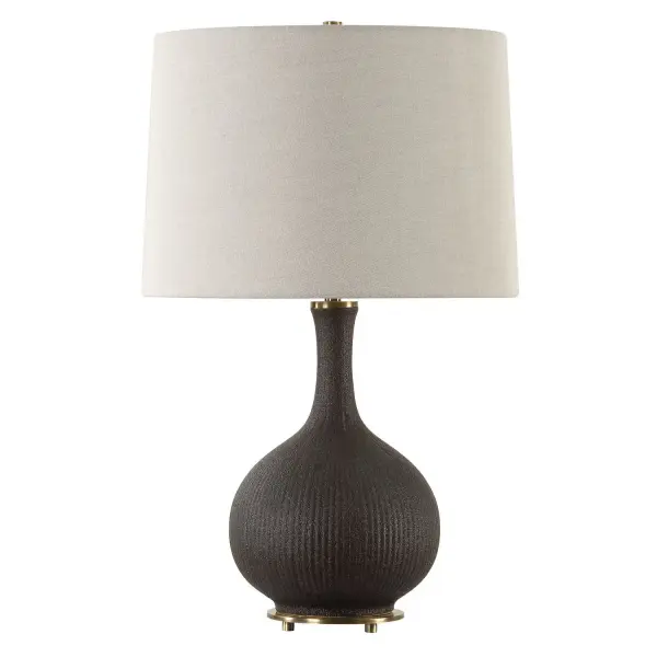 This Ceramic Table Lamp Features Heavily Ribbed Surface With Distressed Texture In A Matte Black Glaze With Rust Undertones. Accented By Plated Brushed Antique Brass Foot And Matching Hardware. The Slightly Tapered Round Hardback Shade Is A Warm Gray Linen Fabric With Natural Slubbing. Collection: Rimini Designer: Osvaldo Mendoza Finish: Brushed Antique Brass Glass: Round Hardback Shade Width: 15.00" Height: 24.25" Length: 15.00" Weight: 7.00 lb Number of Bulbs: 1 Maximum Wattage: 150.00 W Bulb Type: A Voltage: 110.00 V Material: Steel, Ceramic, Fabric Country of Origin: China Safety Rating: Indoor Only