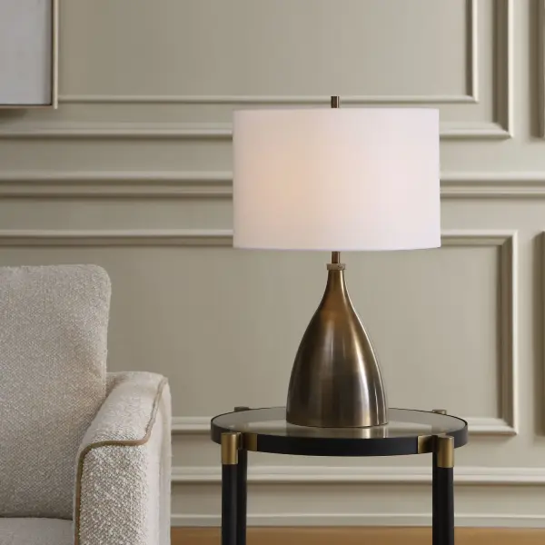 The Jereko Table Lamp Features An Iron Base Finished In Rubbed Bronze With A Small Travertine Stone Detail, Accented By Antique Brass Hardware. The Round Hardback Drum Shade Is Covered In A Crisp White Linen Fabric. Collection: Jereko Designer: John Kowalski Finish: Antique Brass Width: 15.00" Height: 23.50" Length: 15.00" Weight: 4.90 lb Number of Bulbs: 1 Maximum Wattage: 150.00 W Bulb Type: A Voltage: 110.00 V Material: IRON, TRAVERTINE,FABRIC Country of Origin: China Safety Rating: Indoor Only