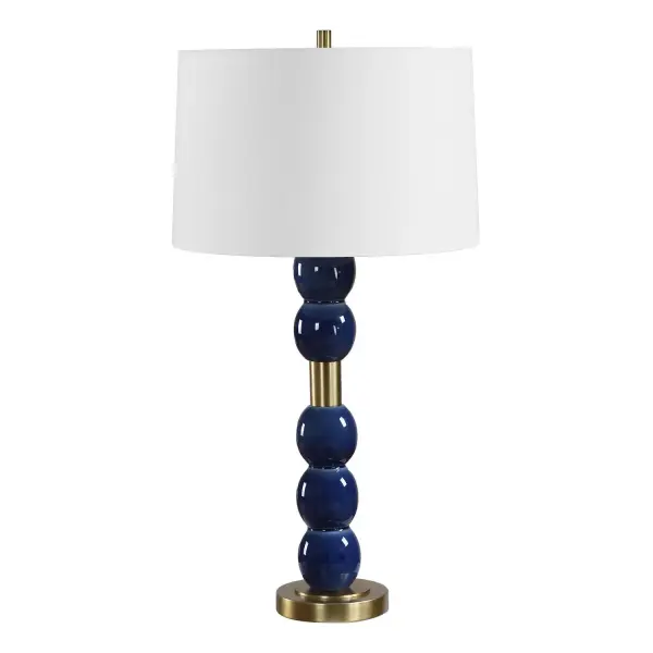 A stacked ceramic orb lamp in glossy denim blue with antique brass accents and a crisp white linen shade—an easy way to add color and warmth to a room.
