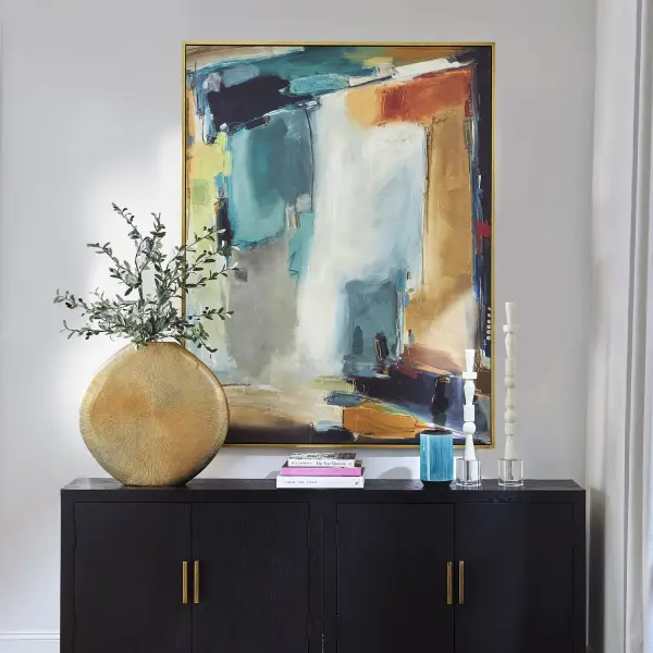 A large hand-framed abstract canvas in ocean green, tan, and golden rod hues with a gold-finished solid wood frame. Versatile orientation adds flexibility for styling.