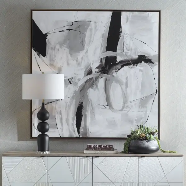 A large-format abstract giclee on canvas in warm tans, grays, and cream with black accents, framed in a bronze gold gallery frame. Hangs horizontal or vertical.