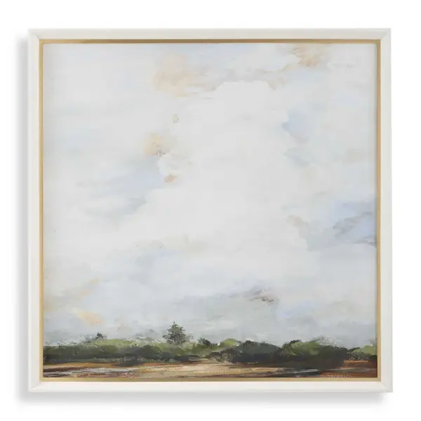 This large-scale landscape print pairs lush green scenery with a cloud-filled sky, framed in white wood with subtle gold leaf detailing for a soft, coastal-inspired accent.