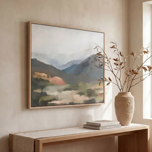 A softly focused, misty landscape print in blues, charcoal, and blush tones, framed in a light oak gallery frame. Handcrafted and printed in the USA.