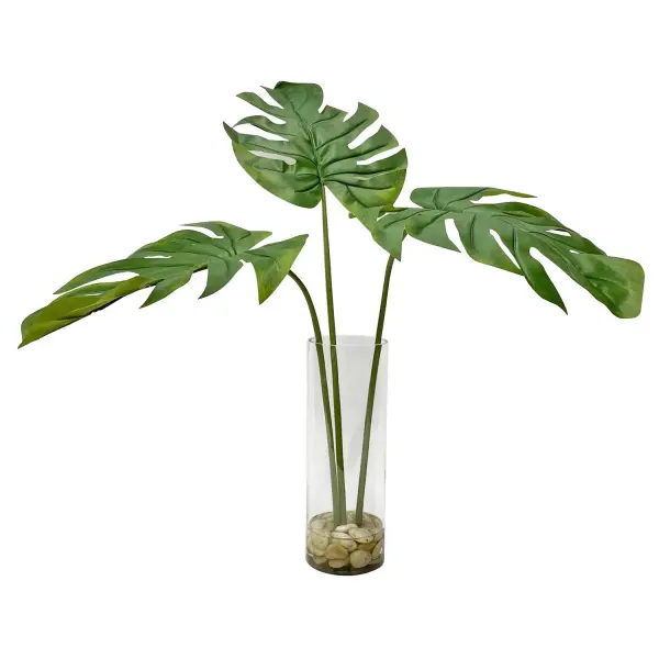 This faux split leaf palm arrangement in a clear glass cylinder with natural stones and faux water offers realistic greenery without upkeep, ideal as a statement floor or table accent.