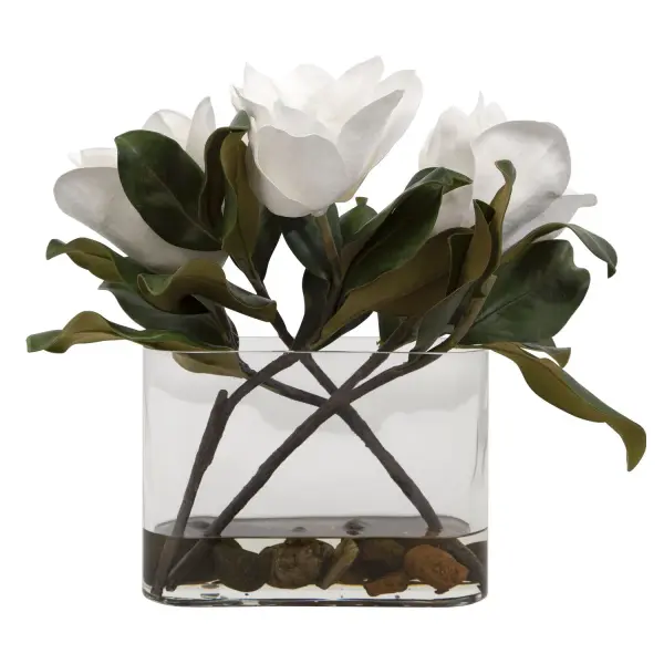 A Trio Of White Magnolia Blooms Are Placed In A Clear Glass Vase With Faux Water And Natural River Stones. Collection: Middleton Finish: White Width: 17.50" Height: 15.75" Length: 8.50" Weight: 6.00 lb Material: Polyfoam, Plastic, Stone, Iron, Glass Country of Origin: China Safety Rating: Indoor Only
