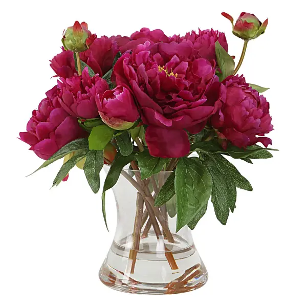 A fluted clear glass vase filled with faux fuchsia peonies and realistic faux water — an easy, low-maintenance decorative accent for tabletops and shelves.