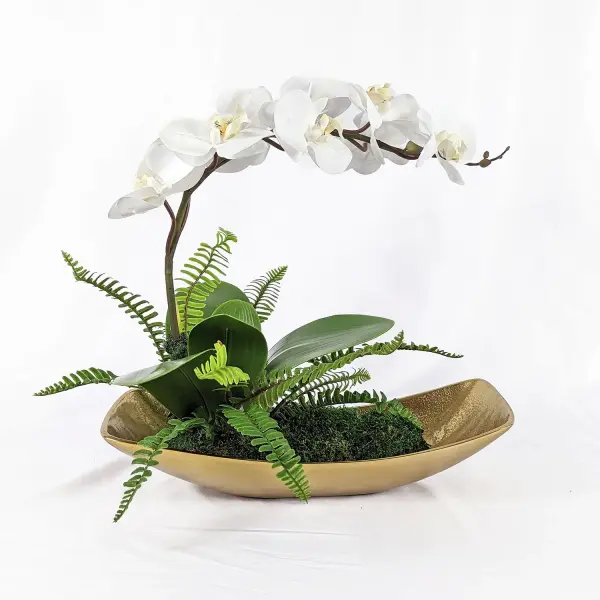 A Graceful, Flowing White Orchid Seems To Float Over A Bed Of Naturally Preserved Moss In A Textured Cast Aluminum Antique Brass Boat. Collection: Transcend Finish: Antique Brass Width: 18.00" Height: 16.00" Length: 16.00" Weight: 5.00 lb Material: Poly Silk, Latex, Aluminum, Foam, Moss Country of Origin: USA Safety Rating: Indoor Only