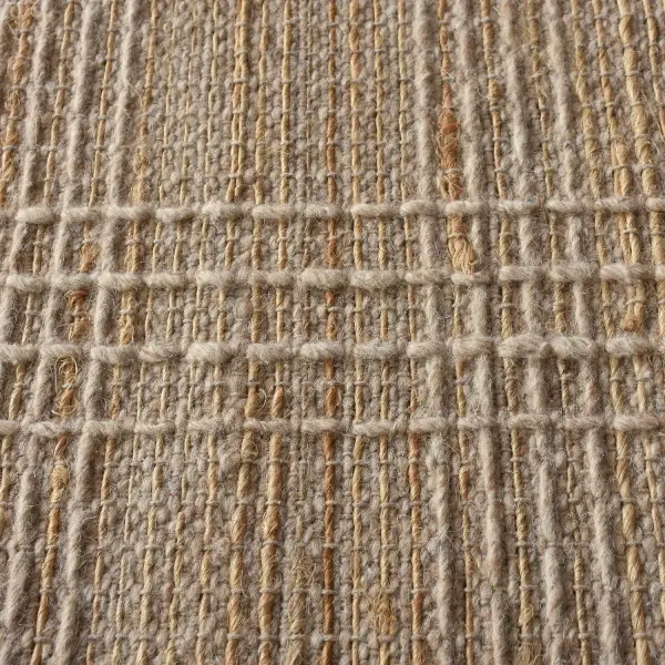 A hand-woven wool and jute rug in beige and natural tones offers understated texture and a versatile, casual-contemporary feel for living spaces.