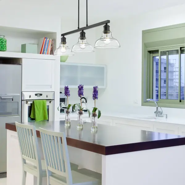 The Carver 3-Light Island Light combines sleek matte black framing with clear glass shades for a contemporary industrial look. Perfect for kitchen islands, it delivers brilliant illumination while showcasing exposed bulbs as part of the design. - alternate view