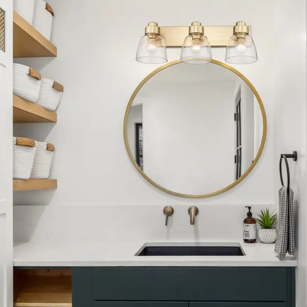 The Golden Lighting Remy 3-Light Vanity combines contemporary luxury with timeless elegance. Its brushed champagne brass finish offers a sophisticated blend of warmth and versatility, while clear glass shades provide brilliant, unobstructed illumination perfect for bathroom tasks. - alternate view