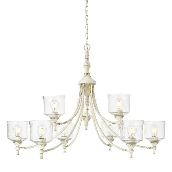 The Keating 9-light chandelier combines farmhouse elegance with artisanal craftsmanship. Its antique ivory finish features a craquelure texture revealing warm gilded undertones, while hammered water glass shades create beautiful refractive light effects.