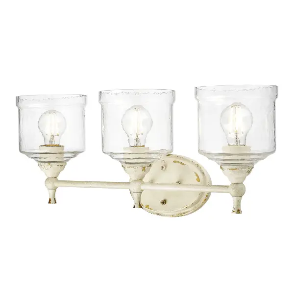 The Keating 3-light vanity combines traditional farmhouse charm with practical bathroom lighting. Its distressed Antique Ivory finish reveals hints of gold beneath, while hammered water glass shades create beautiful light refraction.