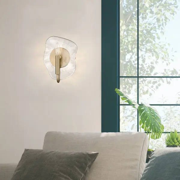 The Samara wall sconce combines warm modern brass with captivating hammered water glass that refracts light into intricate patterns. Damp-rated for bathrooms and hallways, this compact fixture brings nature-inspired artistry to any space. - alternate view