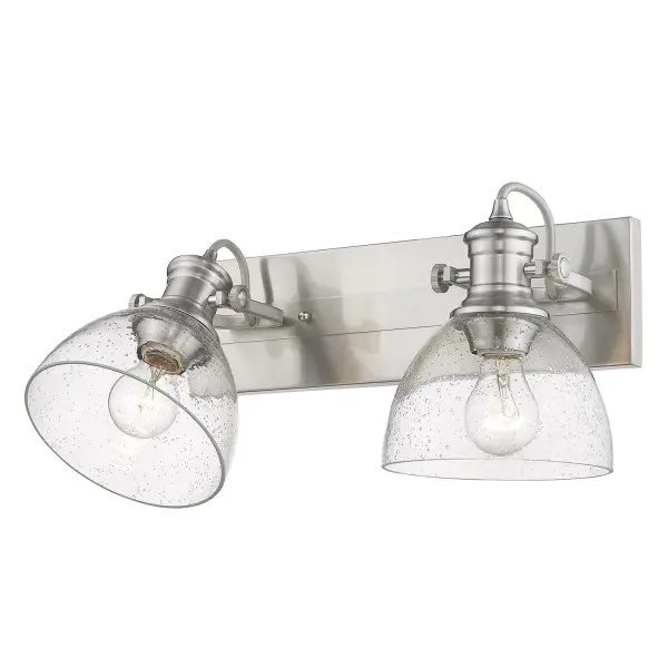 The Hines 2-Light Vanity combines vintage-inspired design with practical features. Its seeded glass shades and pewter finish create a warm, sophisticated glow while adjustable directional heads let you customize lighting angles.
