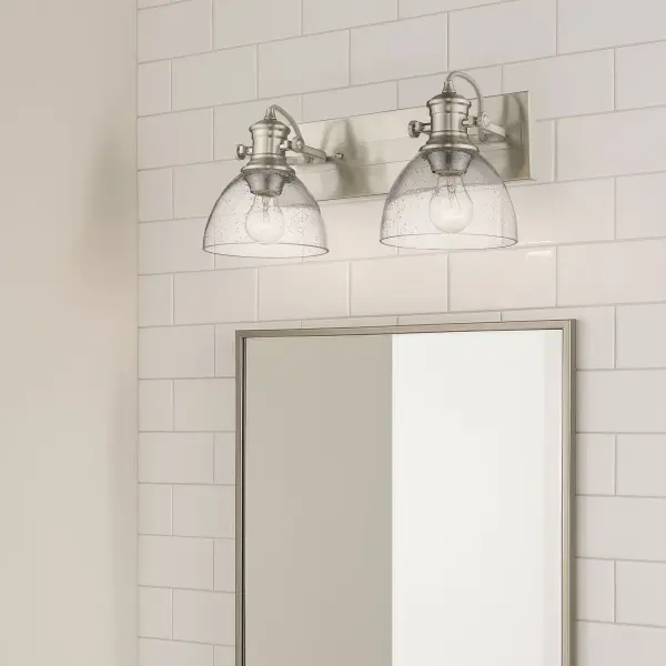 The Hines 2-Light Vanity combines vintage-inspired design with practical features. Its seeded glass shades and pewter finish create a warm, sophisticated glow while adjustable directional heads let you customize lighting angles. - alternate view