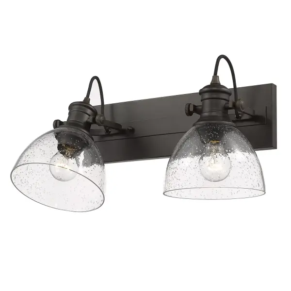 The Hines 2-Light Vanity combines vintage-inspired seeded glass with a warm rubbed bronze finish, creating an inviting farmhouse aesthetic. Adjustable directional heads offer customizable lighting, while the damp rating ensures durability in moisture-prone spaces.