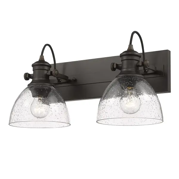 The Hines 2-Light Vanity combines vintage-inspired seeded glass with a warm rubbed bronze finish, creating an inviting farmhouse aesthetic. Adjustable directional heads offer customizable lighting, while the damp rating ensures durability in moisture-prone spaces. - alternate view